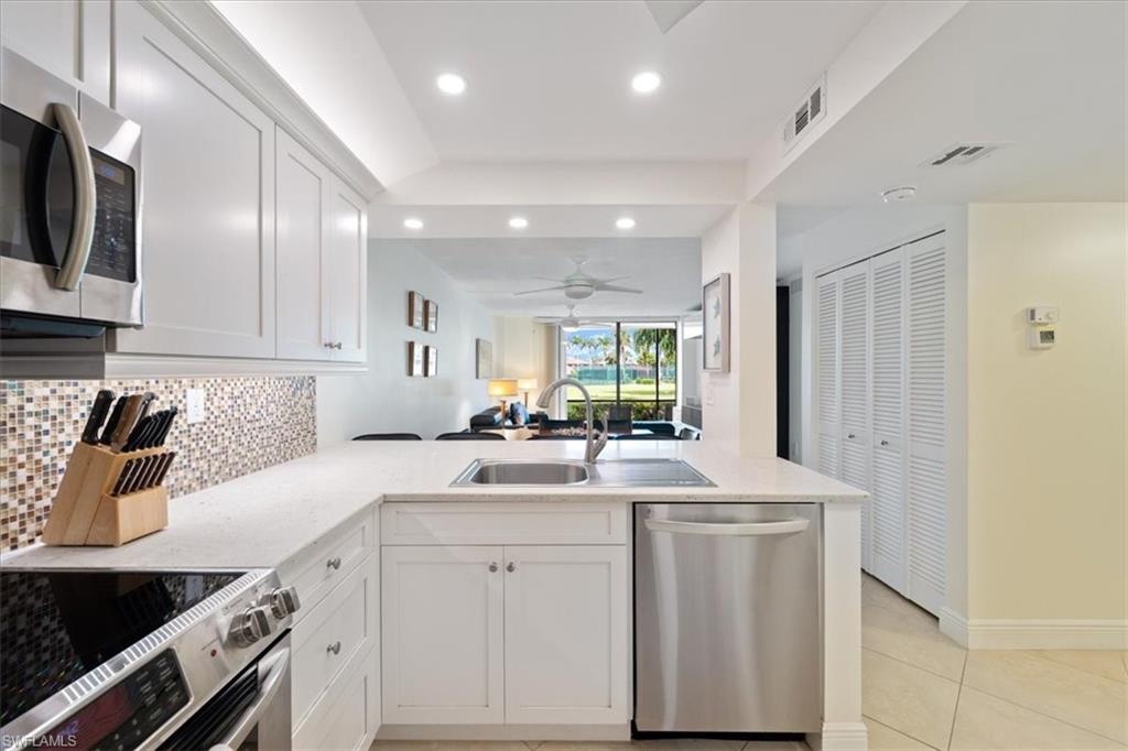 Kitchen featuring open floor plan, appliances with stainless steel finishes, white cabinets, recessed lighting, and a peninsula