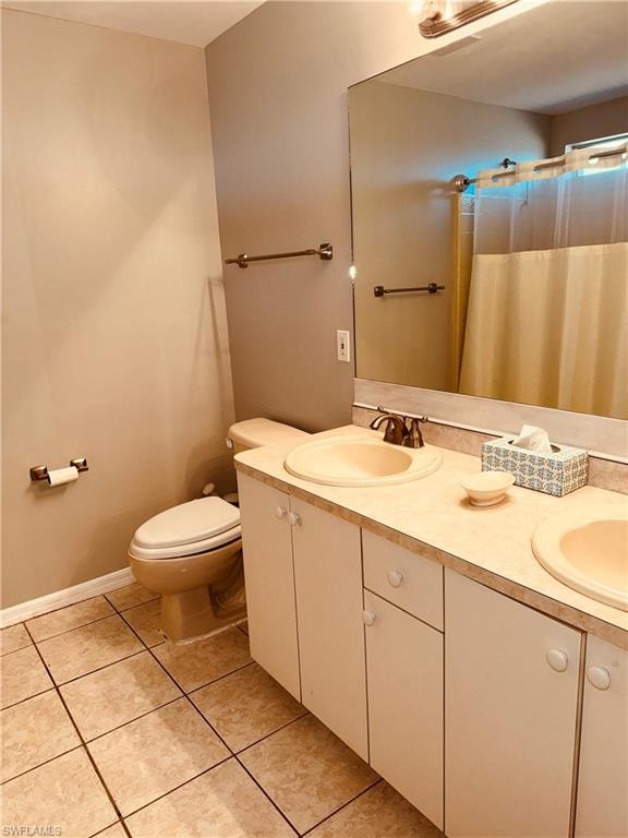 Bathroom with double vanity, curtained shower, and light tile patterned floors