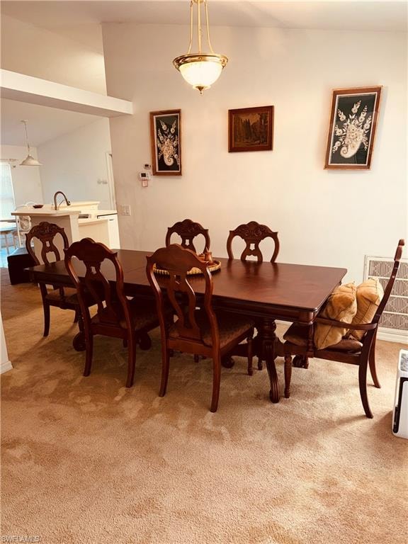 Dining room featuring light colored carpet and vaulted ceiling