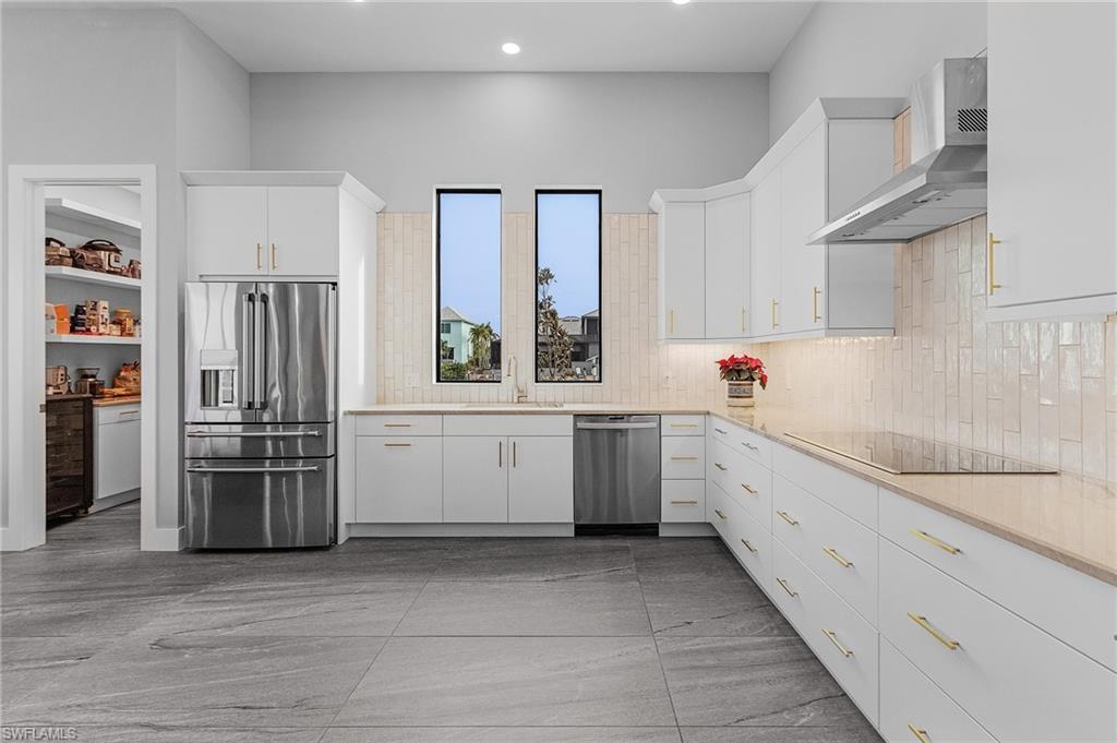 Kitchen featuring white cabinetry, sink, wall chimney exhaust hood, and stainless steel appliances