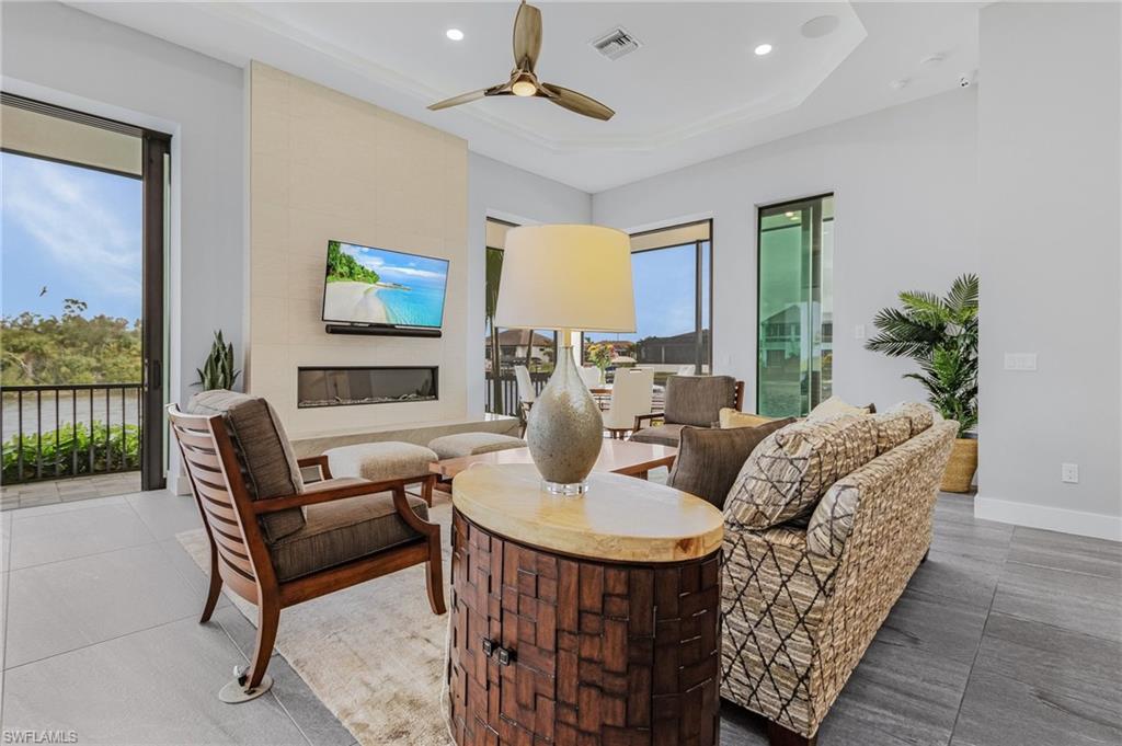 Tiled living room featuring ceiling fan, a fireplace, and a healthy amount of sunlight