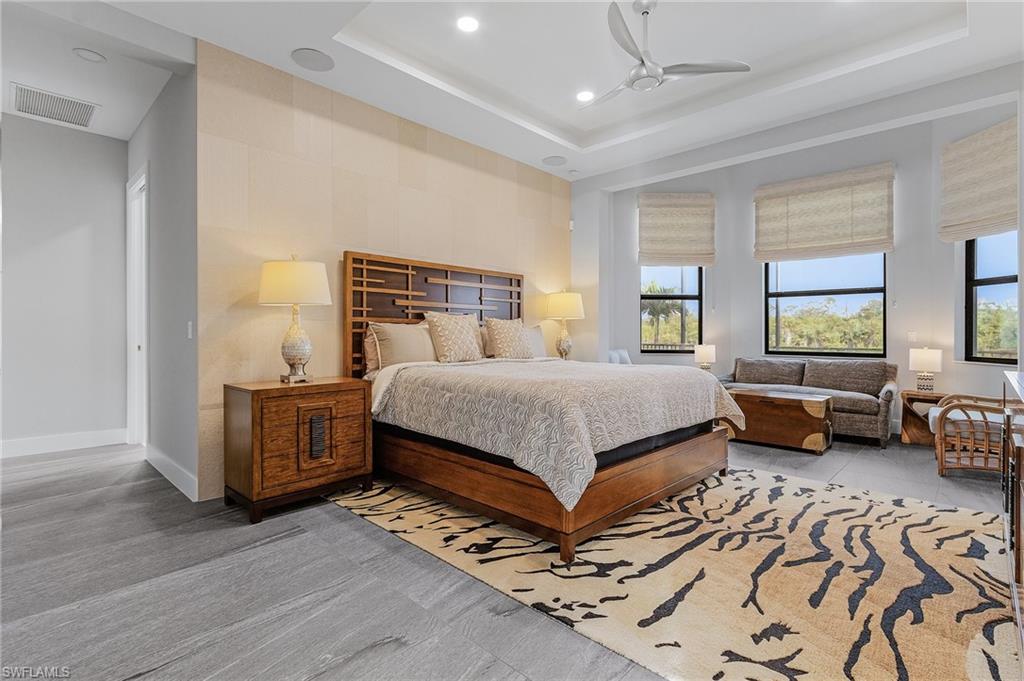 Bedroom with a tray ceiling, multiple windows, and ceiling fan