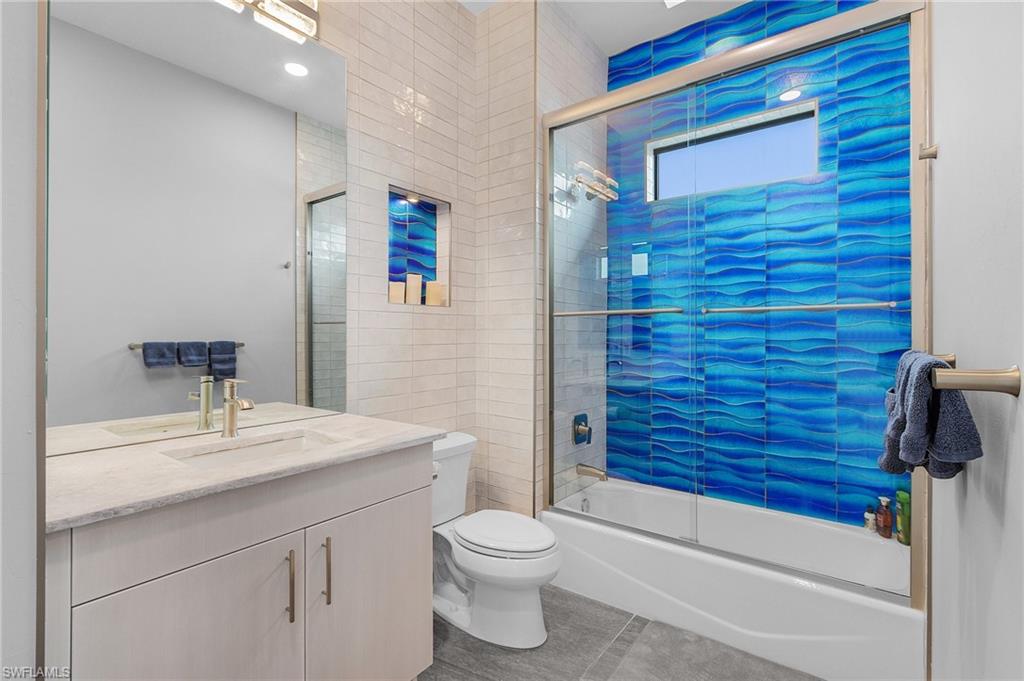 Full bathroom with tile patterned flooring, vanity, toilet, and bath / shower combo with glass door