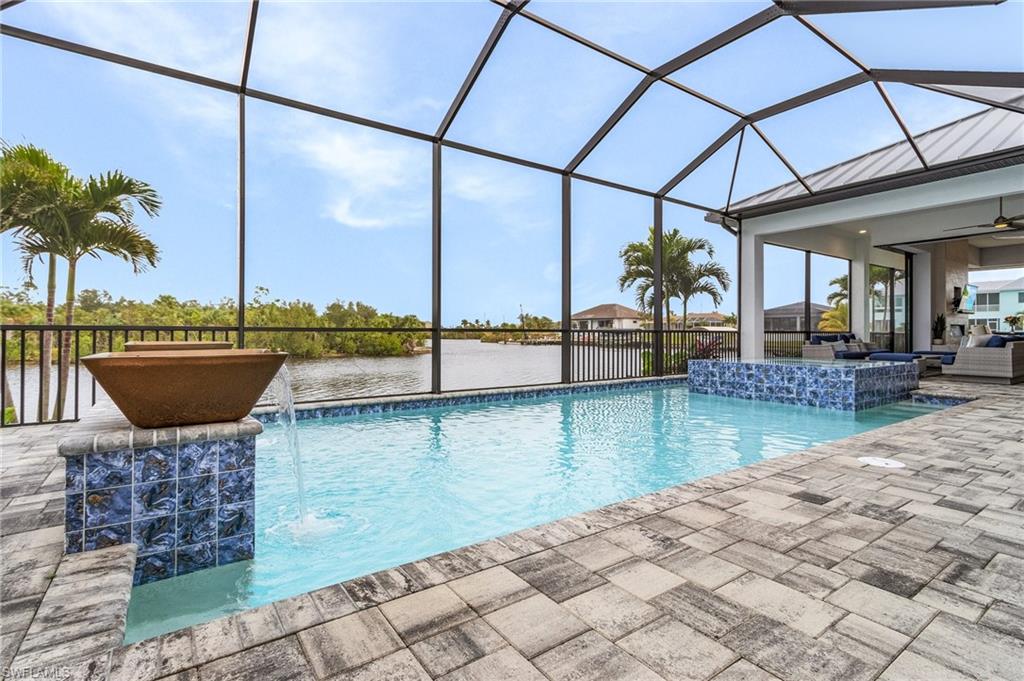 View of swimming pool featuring pool water feature, a lanai, a water view, and a patio