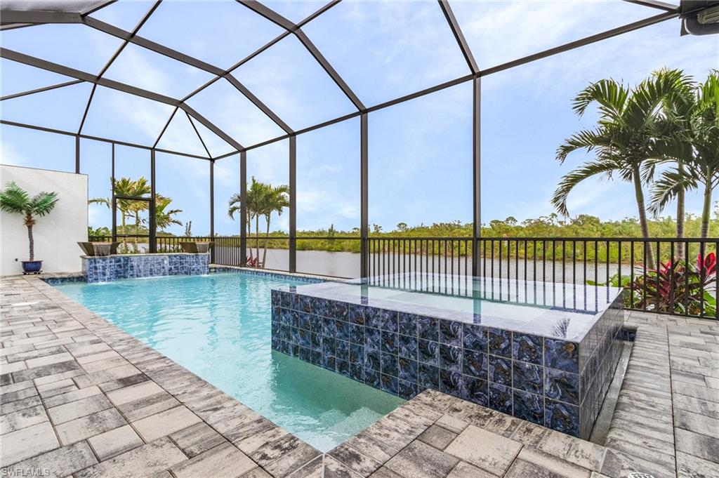 View of swimming pool with a lanai, pool water feature, a water view, and a hot tub