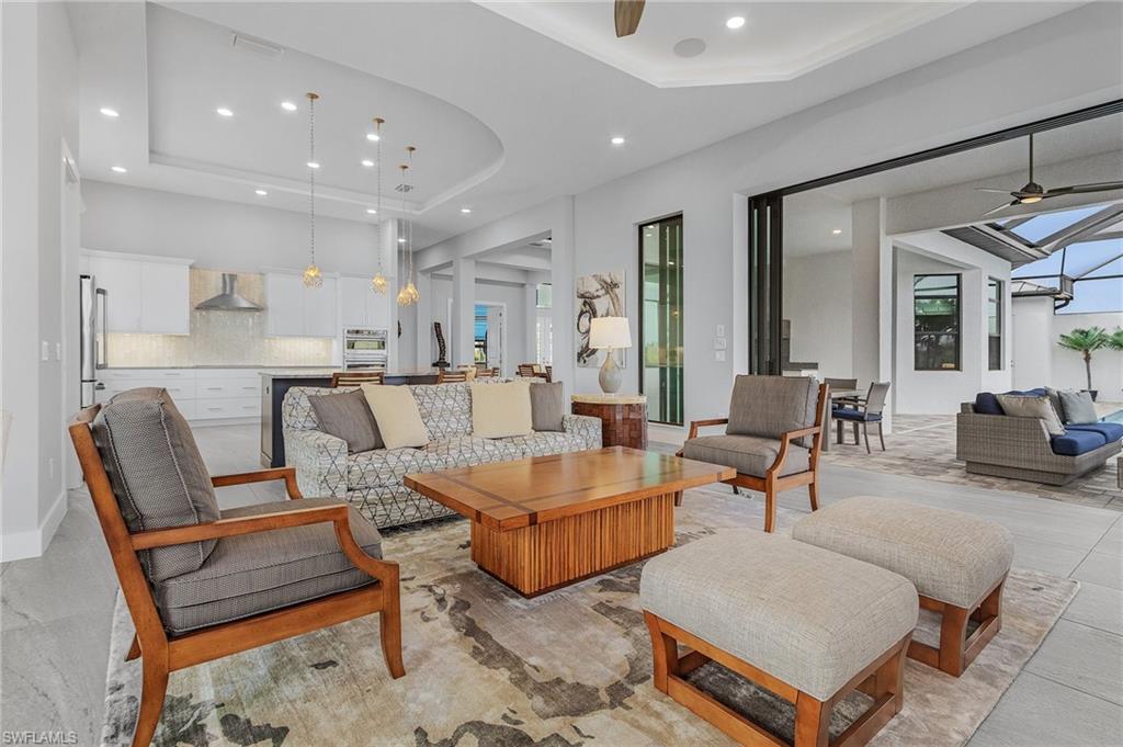 Living room with a tray ceiling, a wealth of natural light, and ceiling fan