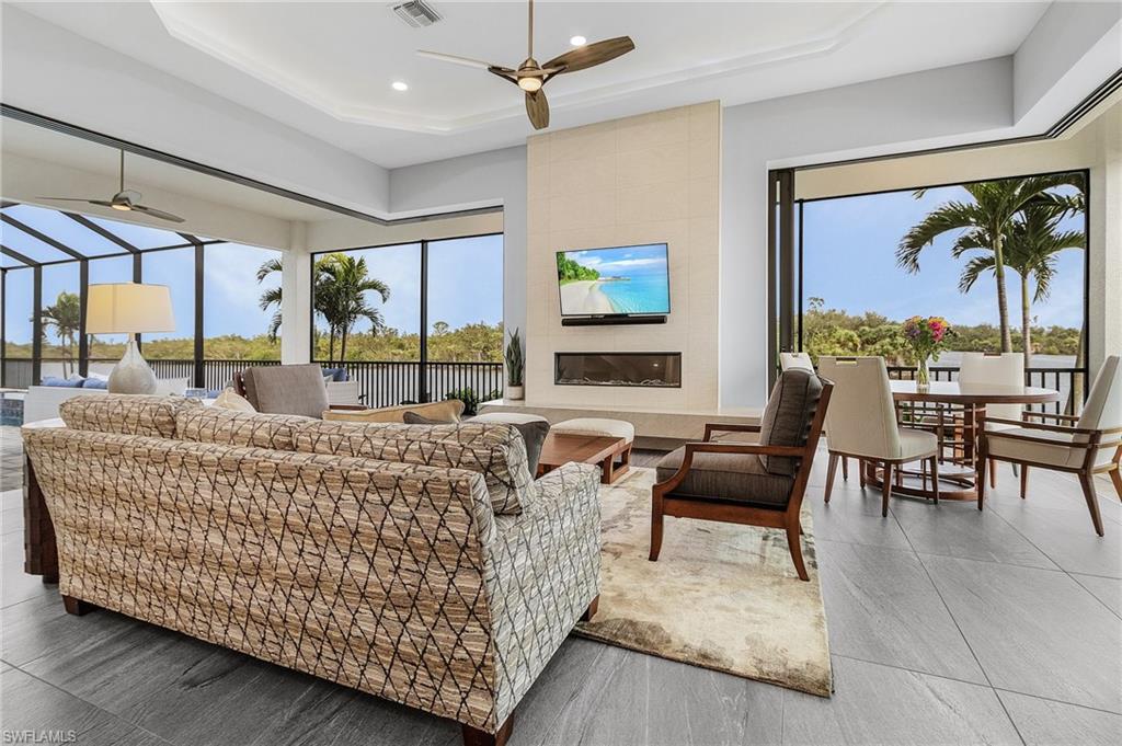 Living room with a tray ceiling, a tile fireplace, and plenty of natural light