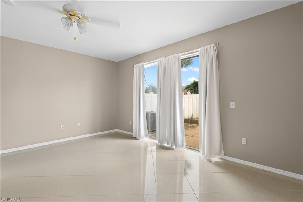 Expansive room featuring large format tile flooring, neutral wall tones, and a ceiling fan with light fixture