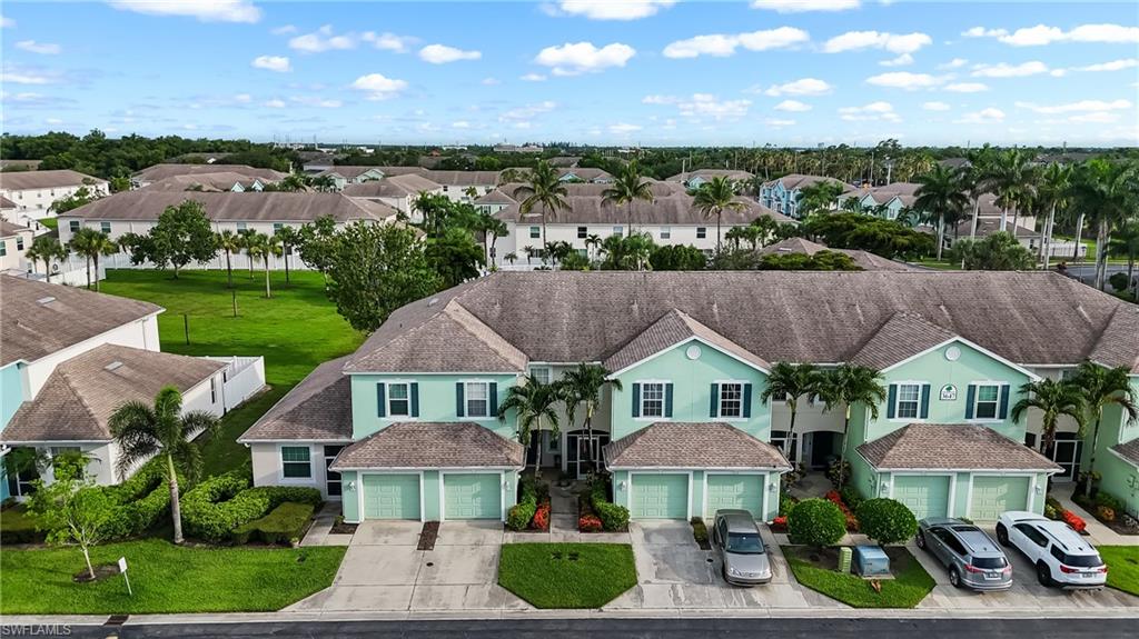 Townhome exterior featuring light green siding, dark window shutters, and a shingle roof