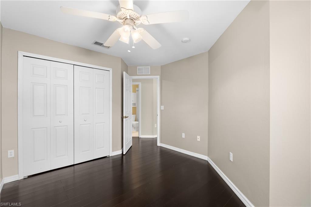 Interior room featuring rich wood-finish flooring, light neutral wall paint, and white bi-fold closet doors