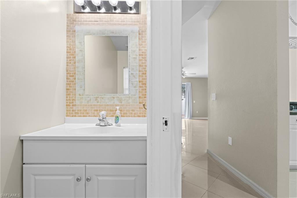 Vanity with white cabinetry, integrated sink, and chrome faucet