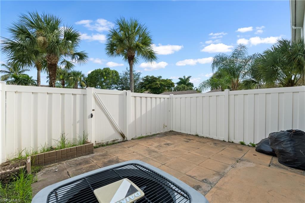 Private patio area featuring a white privacy fence with gate and paver flooring