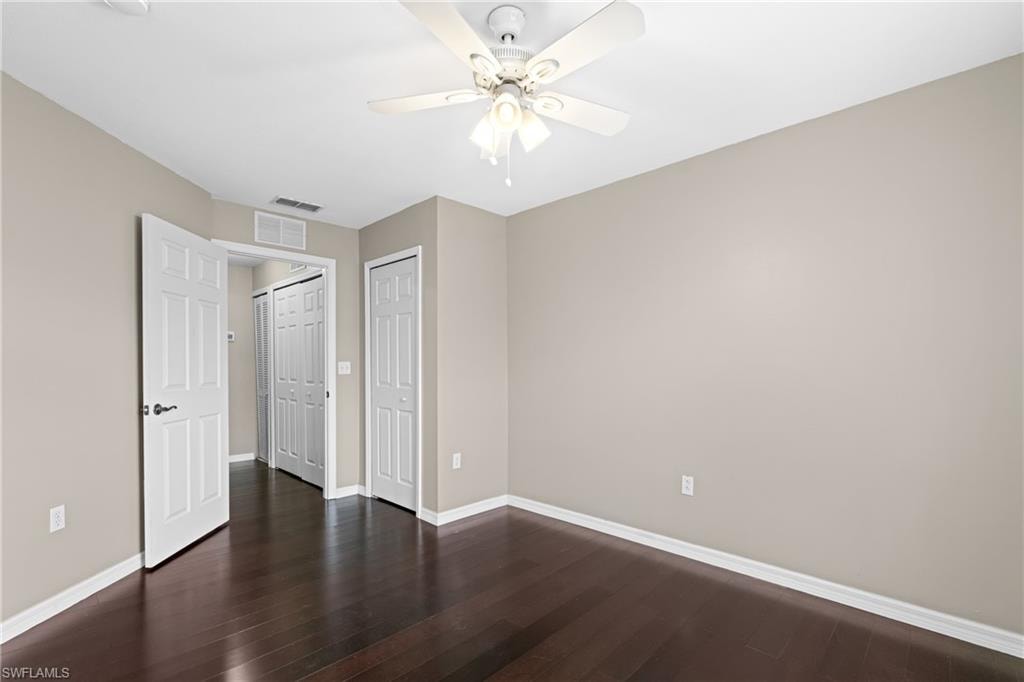Spacious interior room featuring dark wood-finish flooring and neutral painted walls