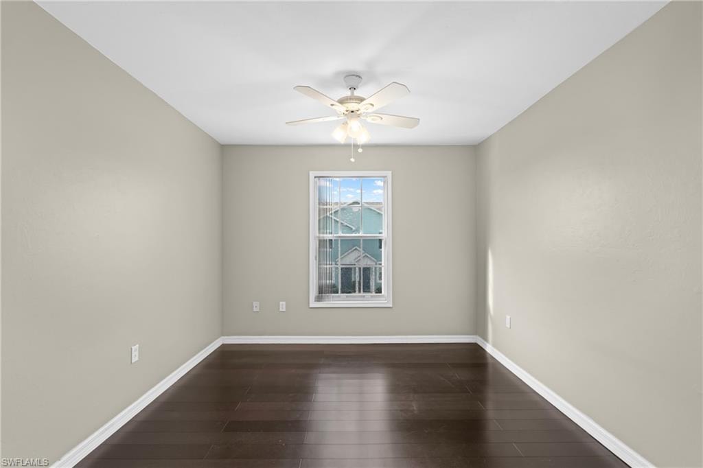 Room featuring dark wood-finish flooring, light neutral-toned walls, and a white ceiling fan with integrated lighting