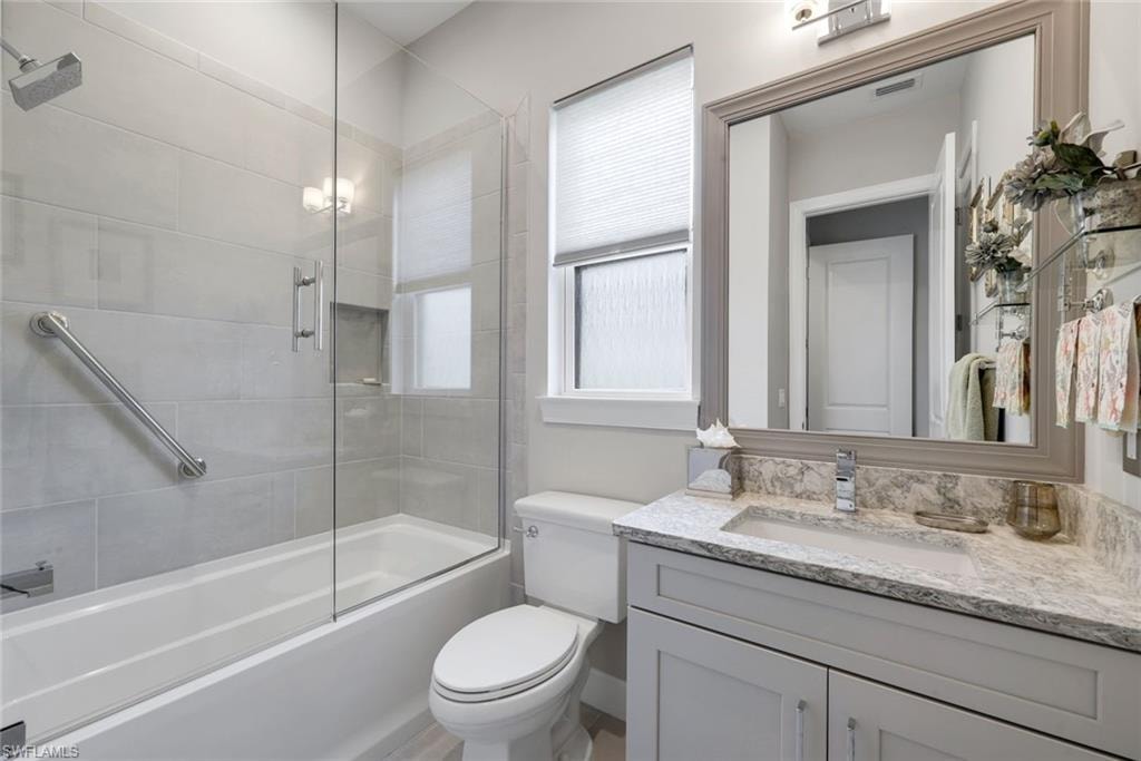 Contemporary bathroom featuring a tub-shower combination with glass enclosure, light gray subway tile surround, and a built-in shower niche