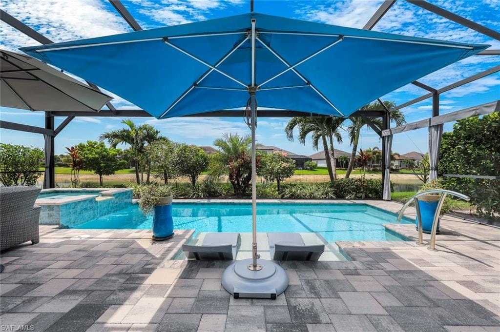 Screened lanai featuring a swimming pool, integrated spa, and pavers