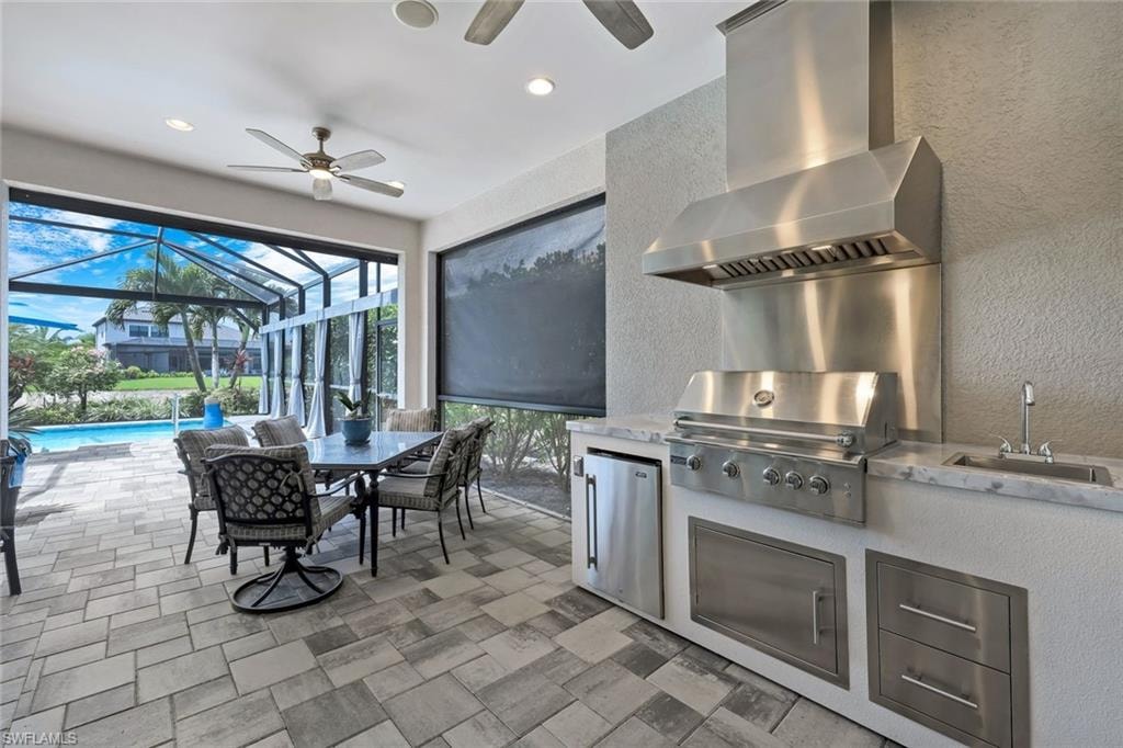 Outdoor kitchen featuring a built-in grill, stainless steel range hood, and integrated sink