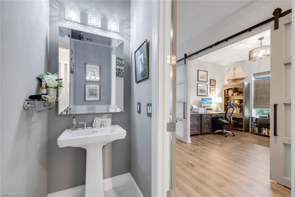 Pedestal sink with polished chrome faucet and an ornate framed mirror
