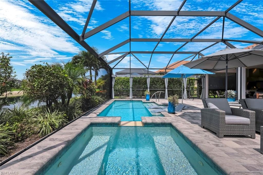Screened-in outdoor living space featuring a dual-level pool and spa, surrounded by paver decking