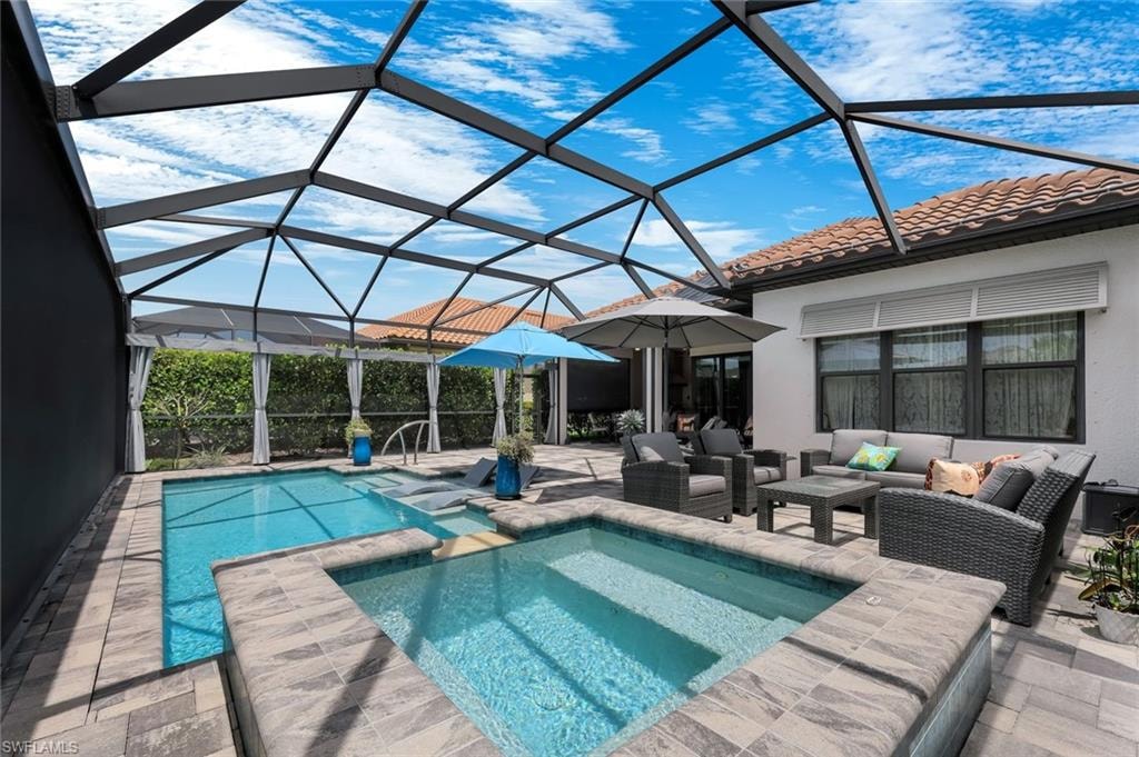 Screened lanai featuring a rectangular pool, integrated spa, and paver decking