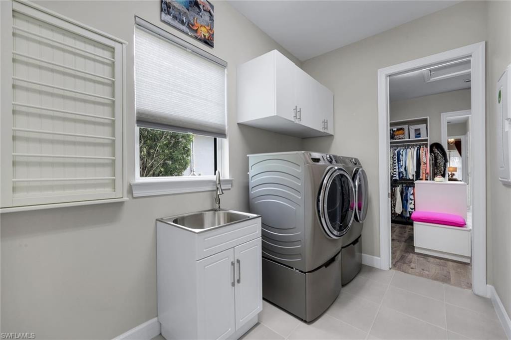Utility room featuring a built-in folding rack, a window with natural light, a stainless steel utility sink with a white shaker-style cabinet, and white upper cabinetry