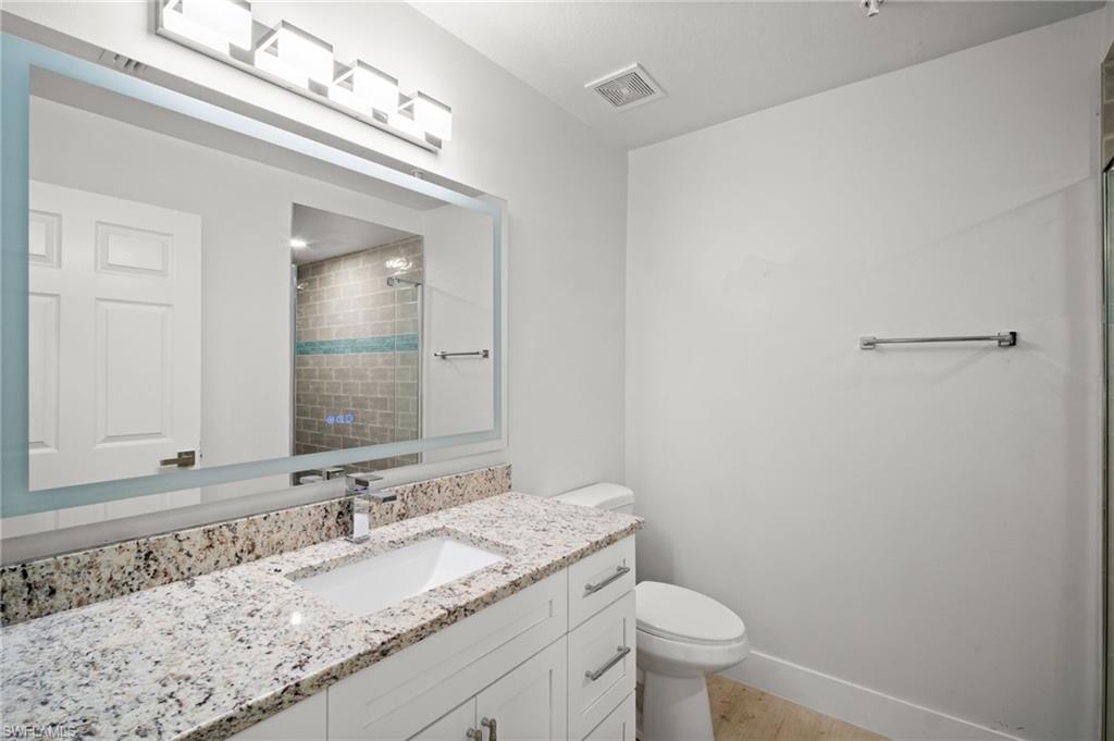 Bathroom with vanity, a tile shower, and light wood-style floors