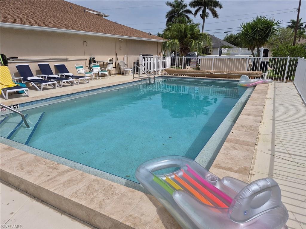 Outdoor swimming pool featuring a tiled interior and integrated steps with handrails