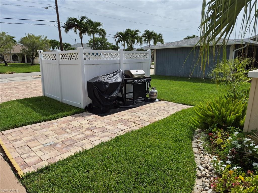 Paved patio area featuring paver flooring and a white privacy fence with lattice accents