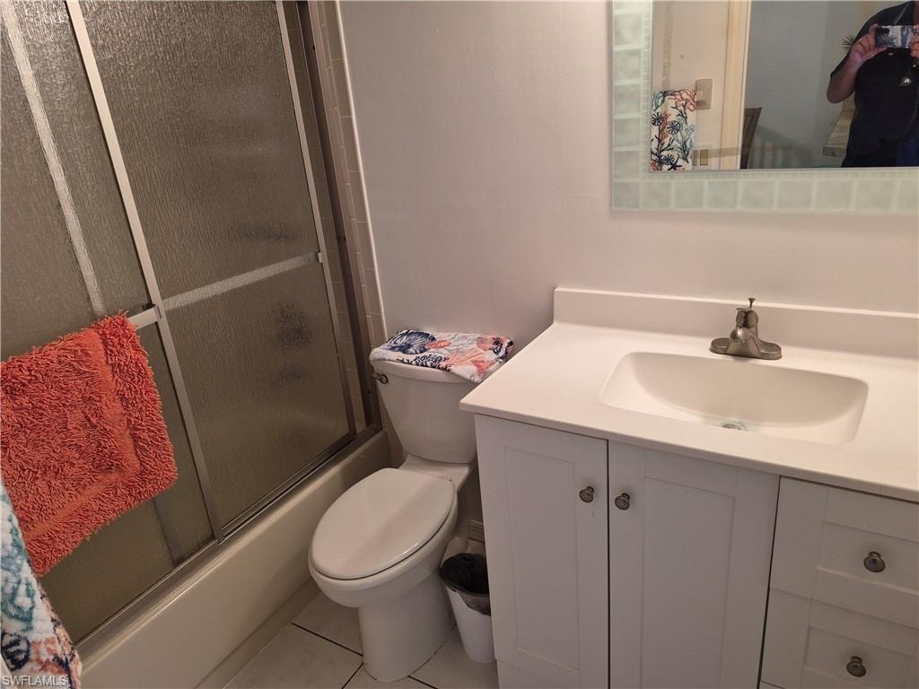 Bathroom vanity featuring a white countertop with integrated sink, brushed nickel faucet, and a tiled mirror frame