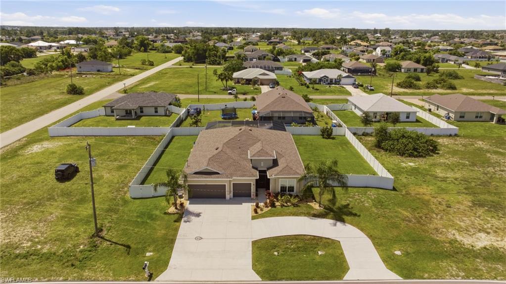 Single-story residence featuring a two-car garage, concrete driveway, and a white perimeter fence