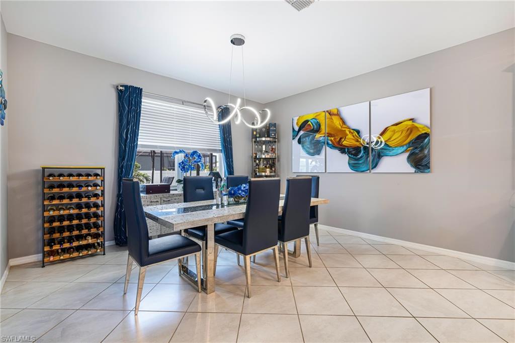 Dining area with tile flooring, a window featuring blinds and drapes, and a contemporary chandelier