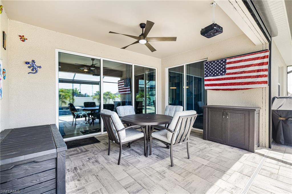Covered patio featuring large format tile flooring, a ceiling fan with integrated lighting, and multiple sliding glass doors
