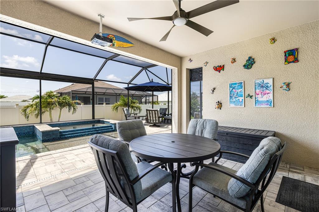 Screened lanai featuring a ceiling fan, light-toned textured walls, and light-toned paver flooring