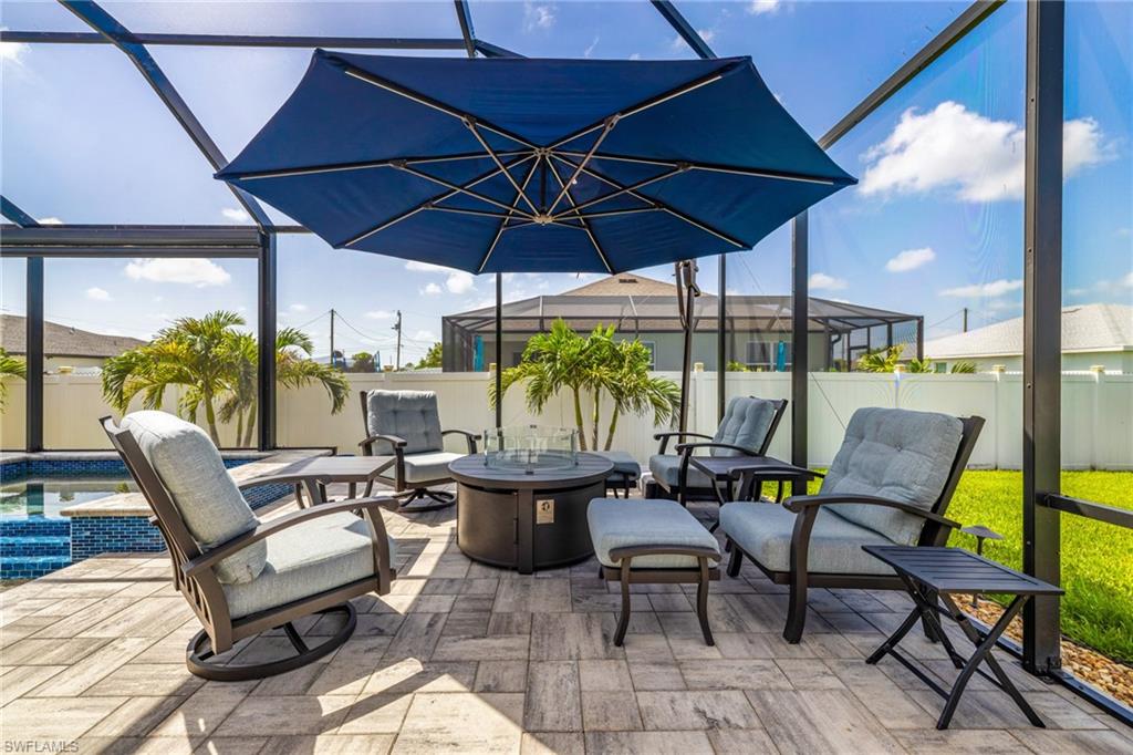 Screened patio featuring a paver deck, a built-in fire pit, and a blue umbrella