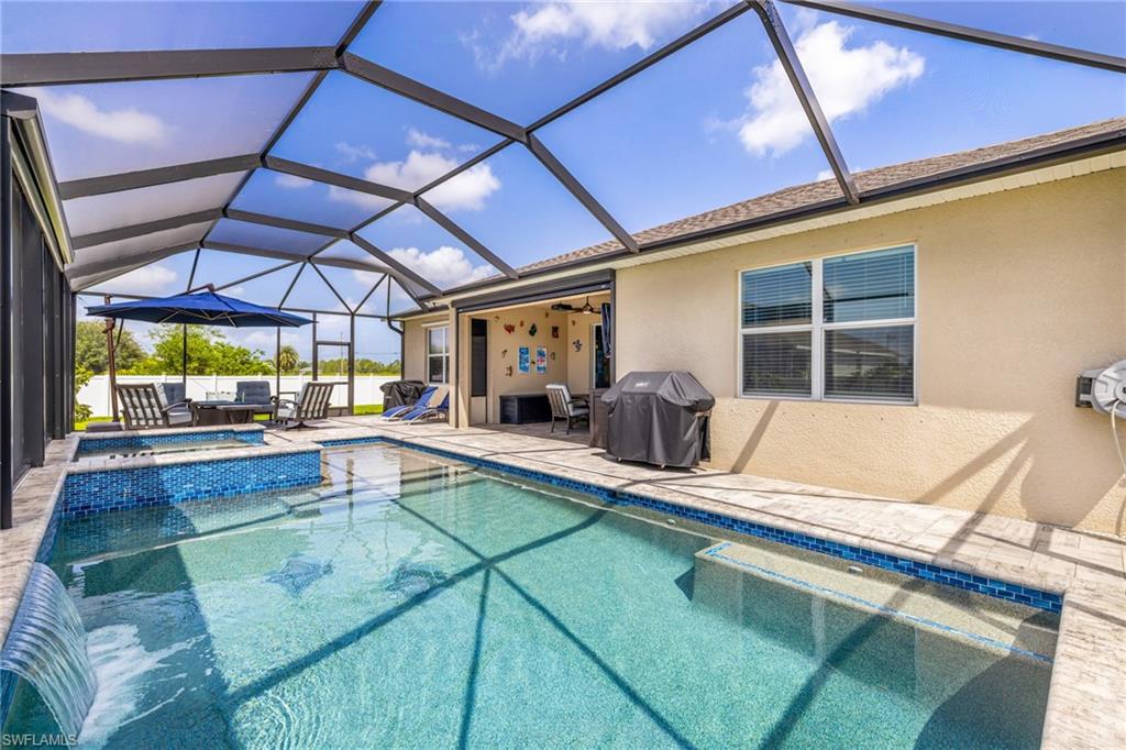 Screened lanai featuring a swimming pool, integrated spa with mosaic tile, and waterfall feature