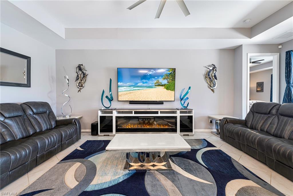 Living area featuring a multi-tiered ceiling, ceiling fan, and tile flooring