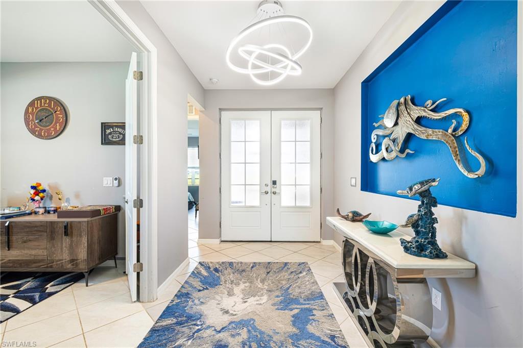 Entryway featuring double French doors with frosted glass panels, a contemporary overhead light fixture, light-toned tile flooring, and a recessed wall accent