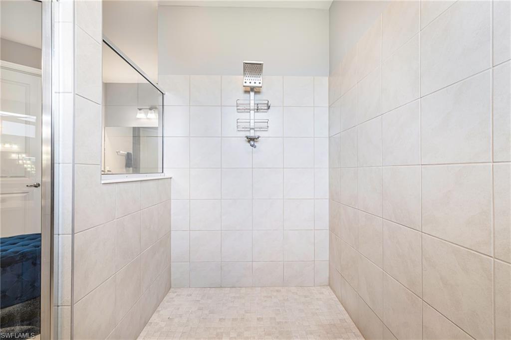 Spacious walk-in shower featuring large format tile walls and mosaic tile flooring
