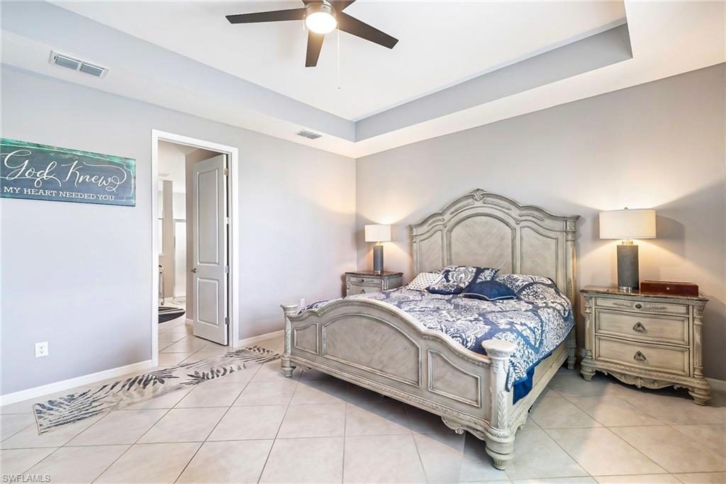 Spacious room featuring tray ceilings, neutral wall tones, and large format tile flooring