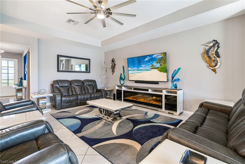 Spacious living area featuring a tray ceiling, contemporary ceiling fan, and tile flooring