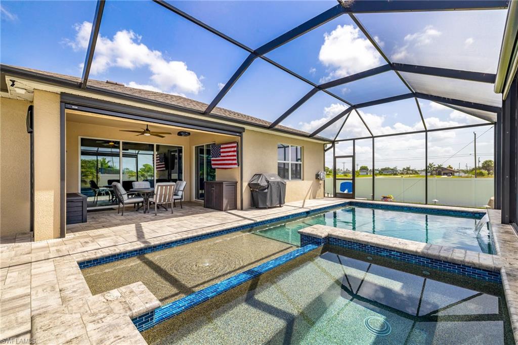 Screened-in outdoor living space featuring a private pool and integrated spa