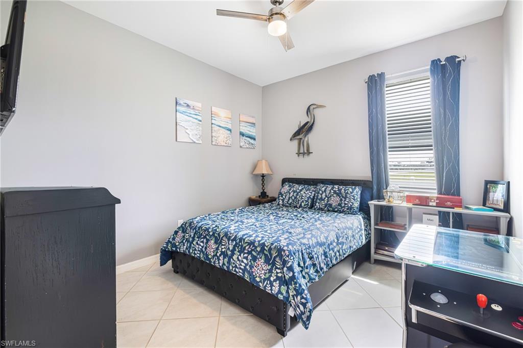 Bedroom featuring light gray walls, tile flooring, a ceiling fan with integrated lighting, and a window with blinds