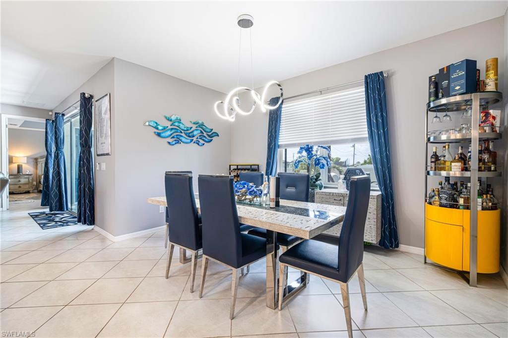 Dining area featuring tile flooring, a modern chandelier, and a large window with blinds