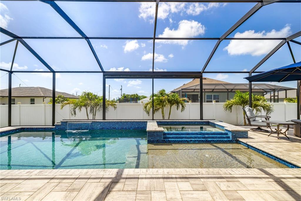 Screened outdoor living space featuring a swimming pool with an integrated spa, mosaic tile accents, and a waterfall feature