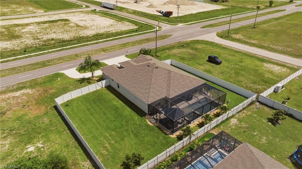 Property featuring a screened pool enclosure, mature palm tree, and a fully fenced perimeter
