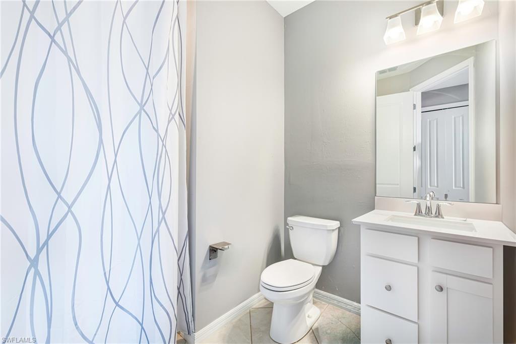 Full bathroom featuring a white vanity with integrated sink, chrome faucet, wall-mounted mirror, and a three-light fixture