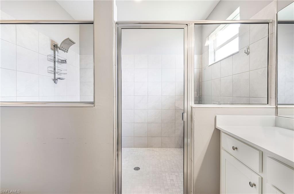 Glass-enclosed shower with subway tile walls and mosaic tile flooring