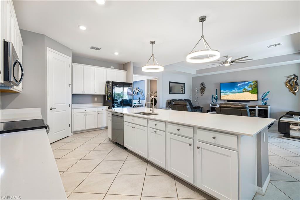 Open-concept kitchen featuring white cabinetry, light-toned countertops, and stainless steel appliances