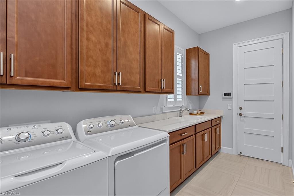 Well-appointed laundry room with abundant cabinetry, workspace, and utility sink.