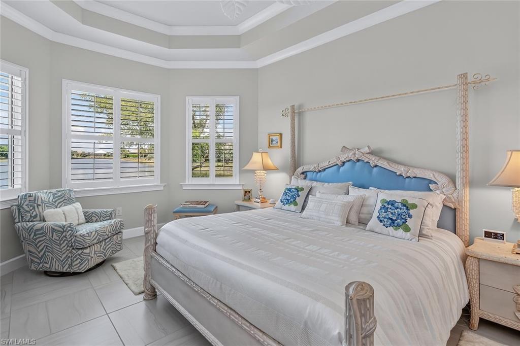 Light-filled primary suite with tray ceilings and tranquil waterfront views.
